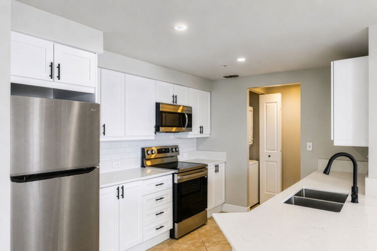 White kitchen with stainless appliances and black faucet at Heritage at Boca Raton